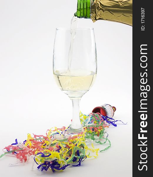 Photo of champagne being poured into a glass with confetti streamers around it. Photo of champagne being poured into a glass with confetti streamers around it