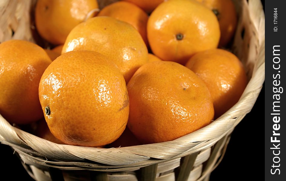 Clementines imported from Spain in a basket on a black background. These are also knows as Satsumas and are grown in southern Louisiana.