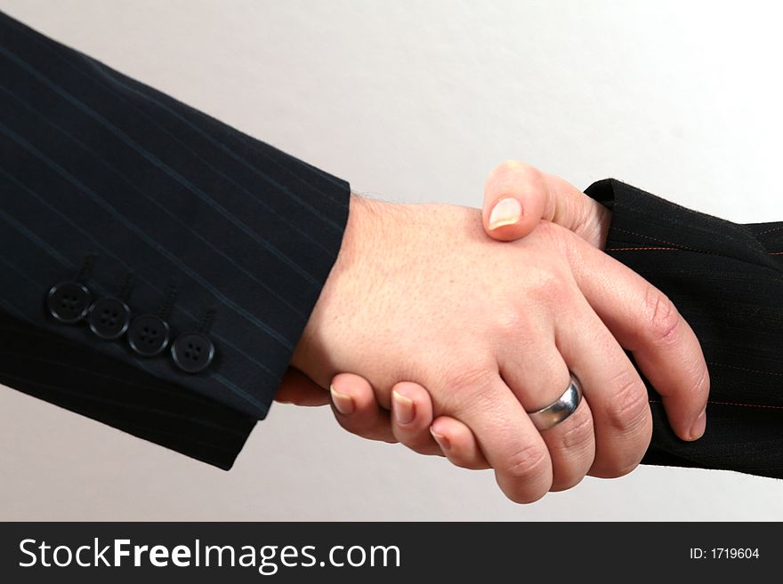 Two business people (male and female) perform a handshake. Two business people (male and female) perform a handshake.