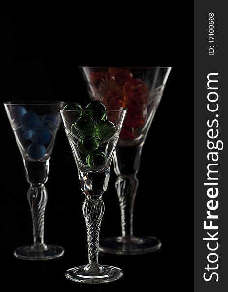 Different glasses full with marbles isolated on black