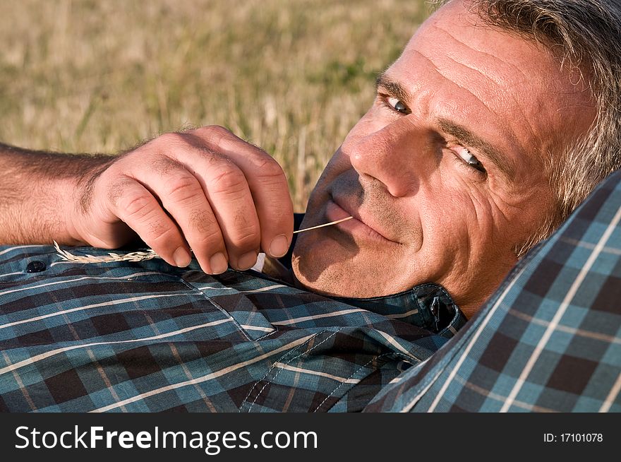 Happy smiling mature man lying down on a meadow and relaxing. Happy smiling mature man lying down on a meadow and relaxing