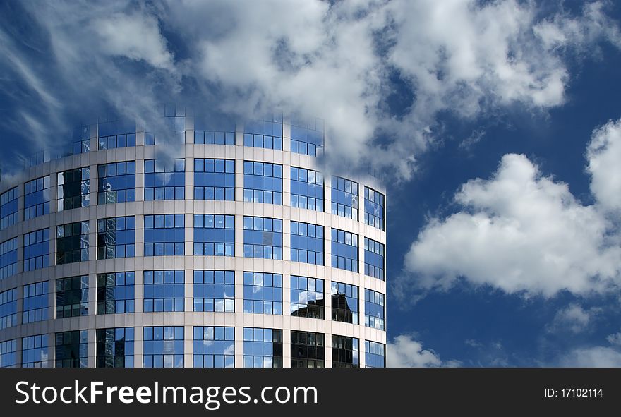 Reflection of a cloudy sky in glass wall of an office building