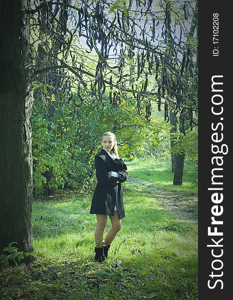 Girl stayning under the dark mysterious tree in the park