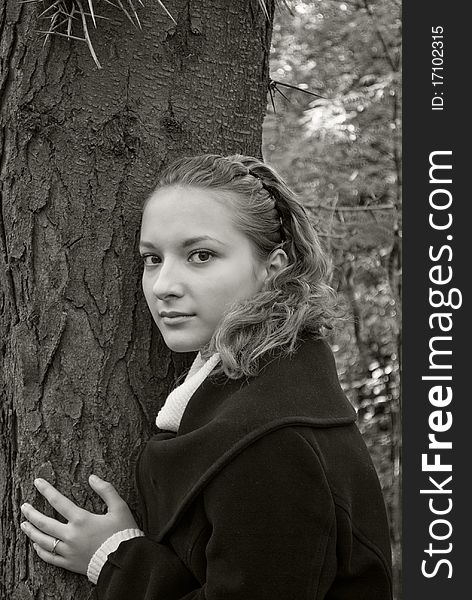 Tender girl near a dark tree trunk. Black and white