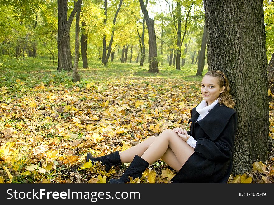 Teen girl sits under the tree leaves in park