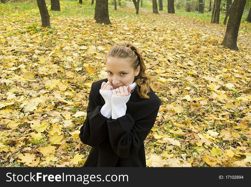 Teen girl warms herself a in cold autumn park