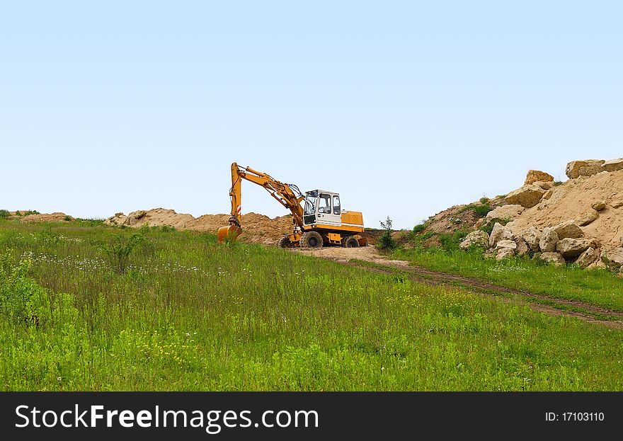 Loader excavator in open sand mine over scenic blue sky