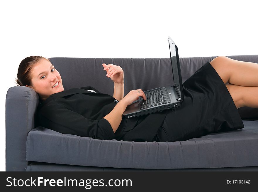 The beautiful businesswoman works at the computer, lying on a sofa