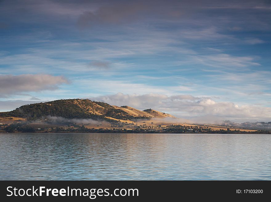 Scenic hills by the ocean in Tasmania covered by morning mist. Scenic hills by the ocean in Tasmania covered by morning mist.