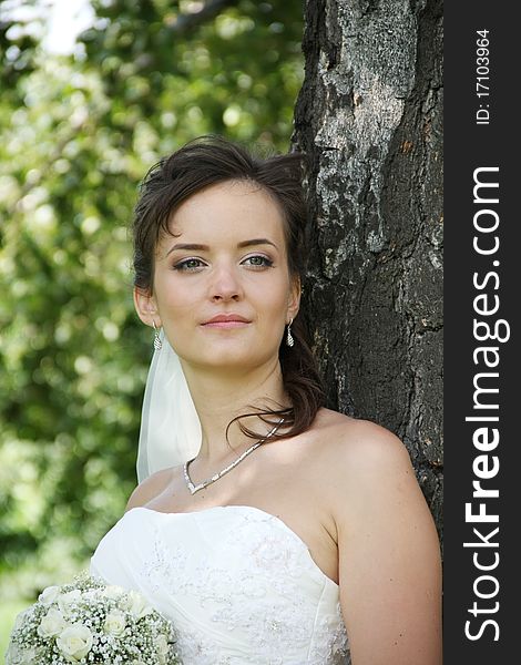 Portrait of Ukrainian fiancee with a wedding bouquet in hands, stands under a birch