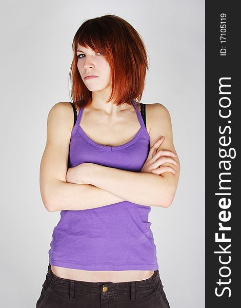 Young redhead girl in purple shirt with crossed hands, dissatisfaction emotion, half body. Young redhead girl in purple shirt with crossed hands, dissatisfaction emotion, half body