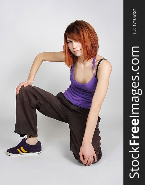 Redhead girl in hip-hop clothes sitting