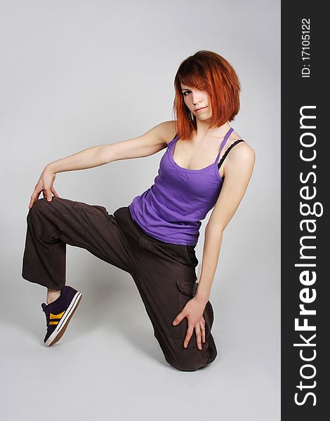 Young redhead girl in hip-hop clothes sitting