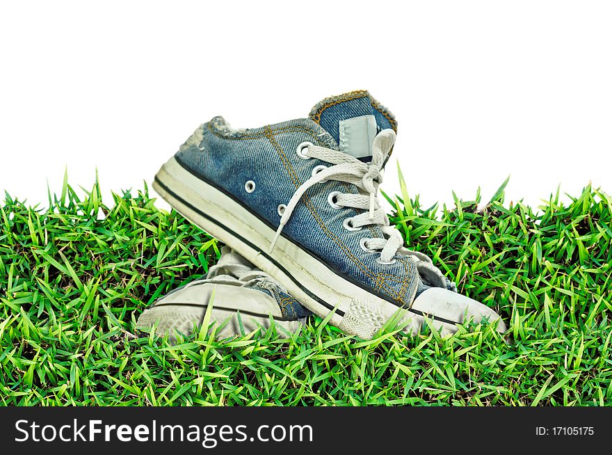 Old, dirty sneakers over spring green grass,white background ,isolated