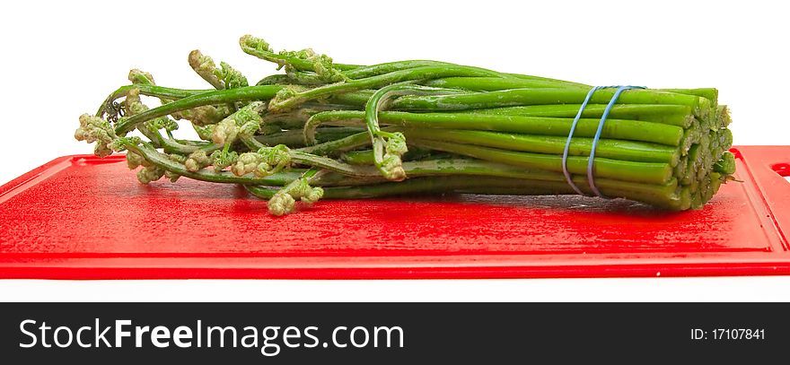 The image of runaways of an edible fern on a kitchen board. The image of runaways of an edible fern on a kitchen board