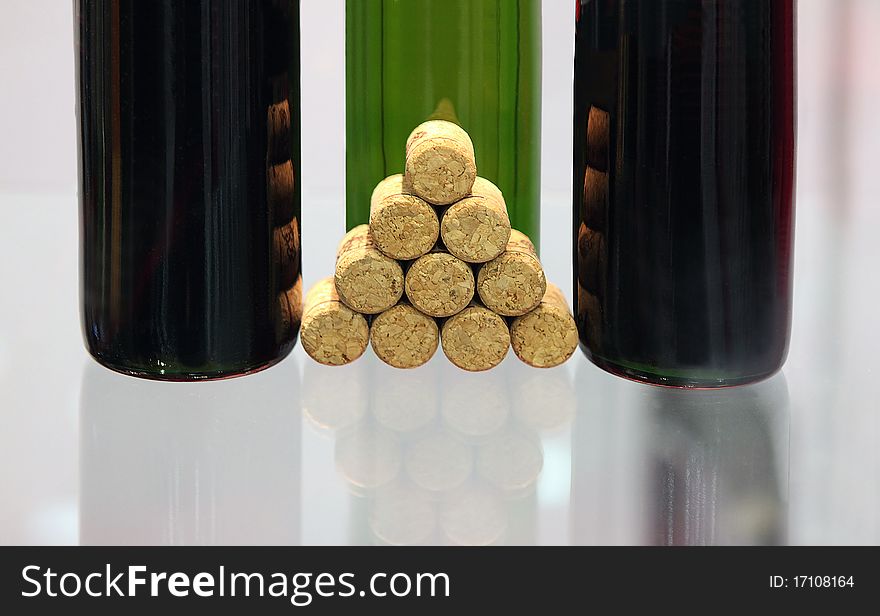 Bottles with wine and wine stoppers on a glass surface