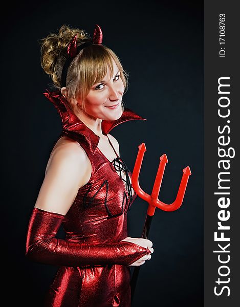 Red devil woman with trident on black background