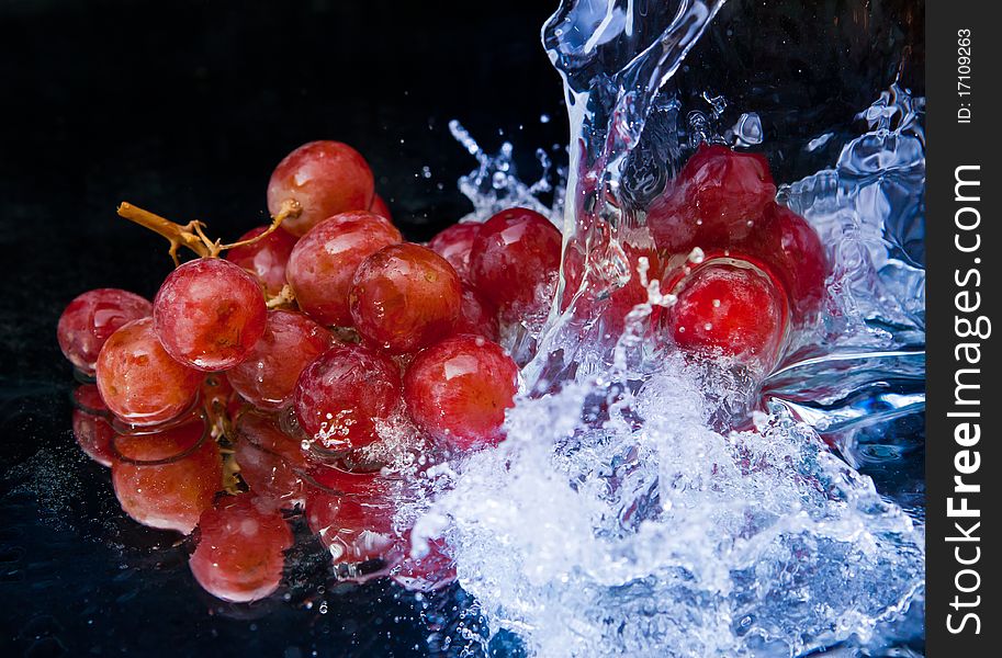 Grapes and splash water over black background