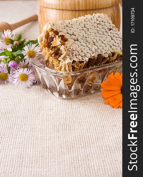 Honey, honeycomb in pot, stick and flowers on sack