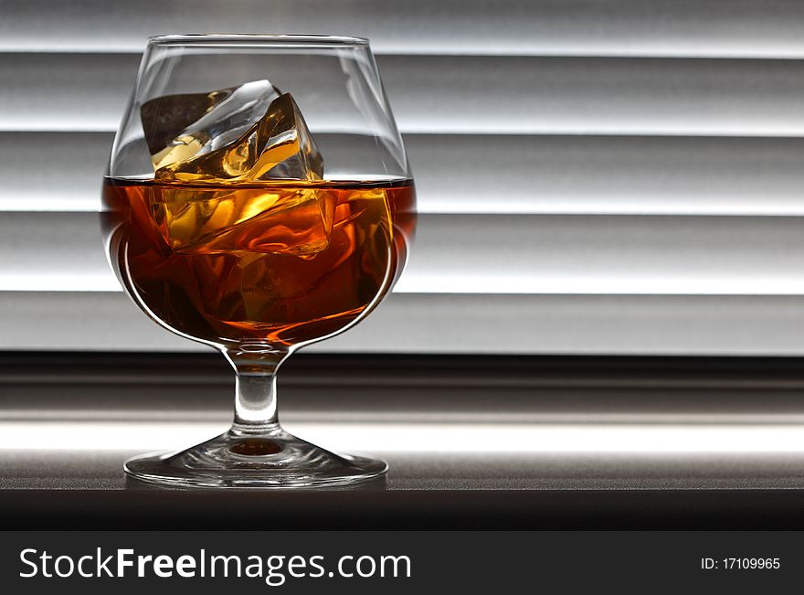 Whisky glass with ice on a window sill