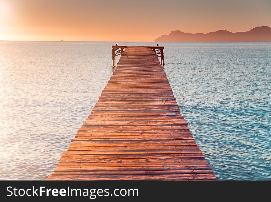 Warm morning light in summer vacation holiday resort. Pier in orange sunrise colors