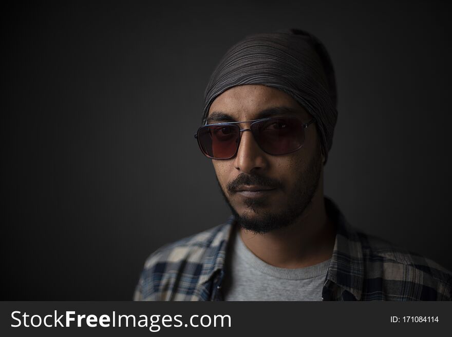Indian Bengali handsome beard macho guy/man/male in cowboy hat and sun glass holding a tobacco pipe  on his mouth in front of a grey copy space studio background. Copy space facial expressions. Indian Bengali handsome beard macho guy/man/male in cowboy hat and sun glass holding a tobacco pipe  on his mouth in front of a grey copy space studio background. Copy space facial expressions
