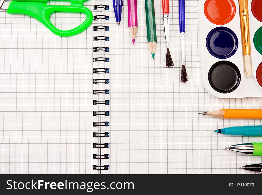 Pencils, pens, paint brush and scissors on paper
