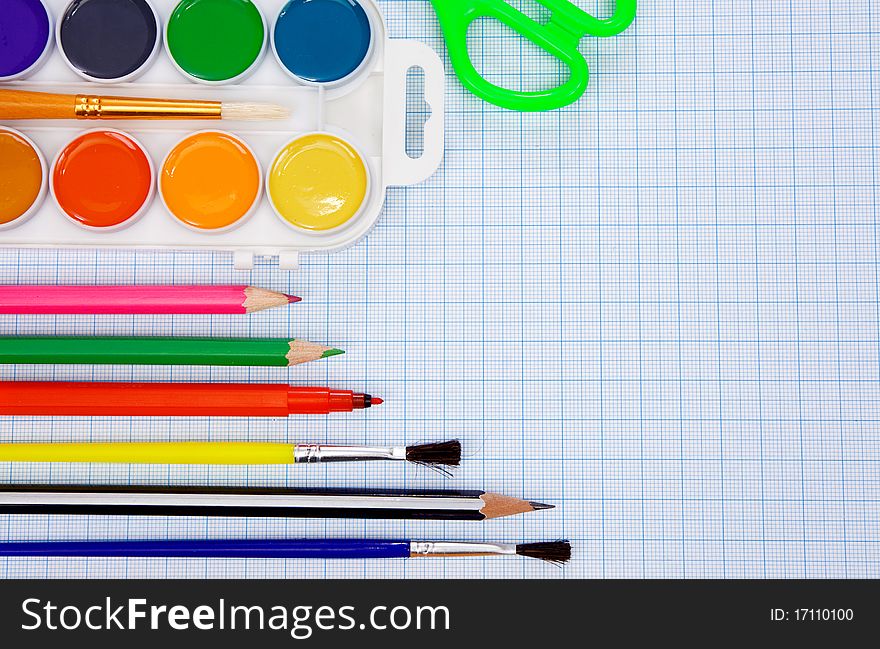 Pencils, felt pens, paint brush and scissors on graph grid paper. Pencils, felt pens, paint brush and scissors on graph grid paper