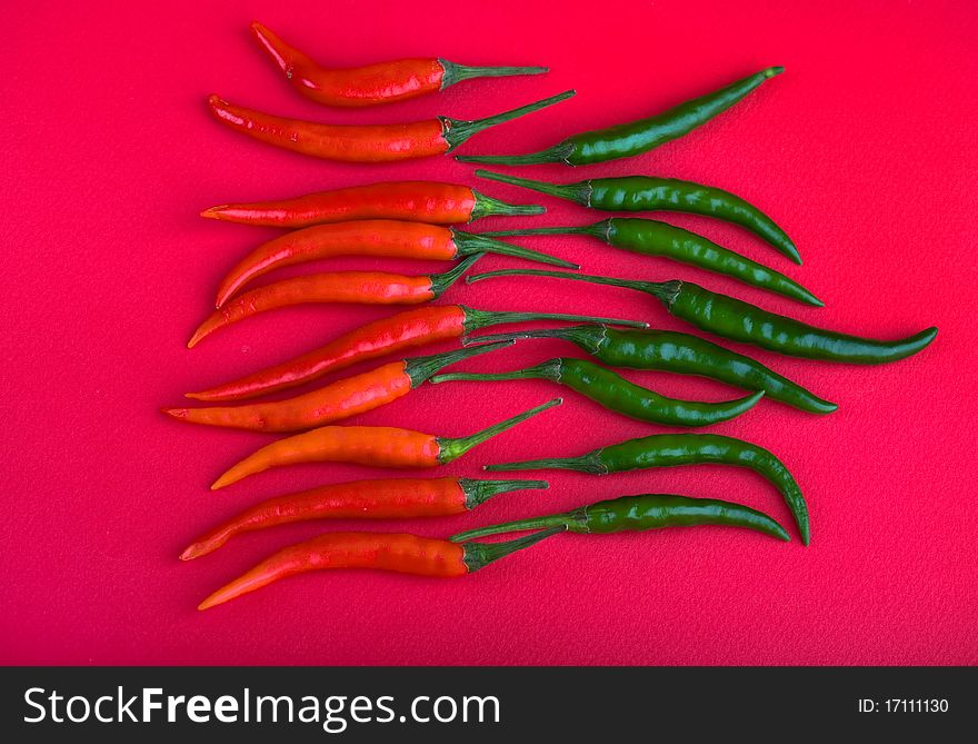 Red and green hot chili peppers on pink background