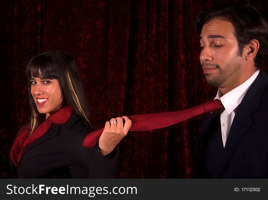 A woman catches a man and leads him by his tie. A woman catches a man and leads him by his tie