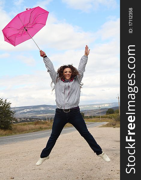 Joyful young lady jumping with bright pink umbrella. Joyful young lady jumping with bright pink umbrella