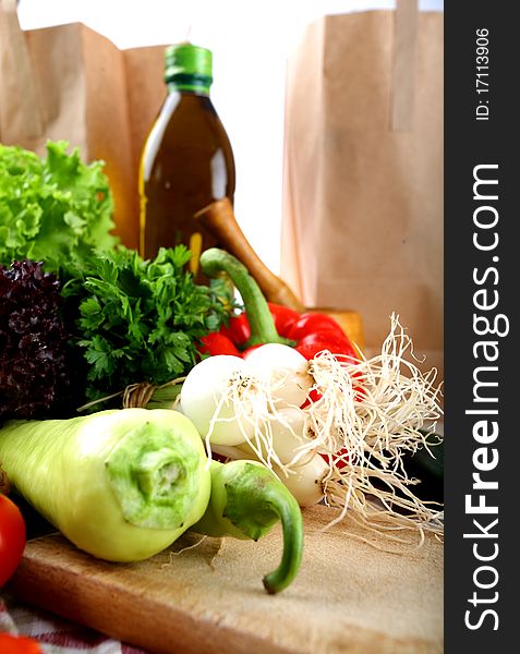 Vegetables, bottle of olive oil and shopping bags placed on a kitchen table. Vegetables, bottle of olive oil and shopping bags placed on a kitchen table