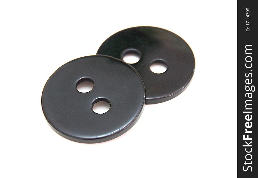 Two black buttons lie on a white background. Two black buttons lie on a white background