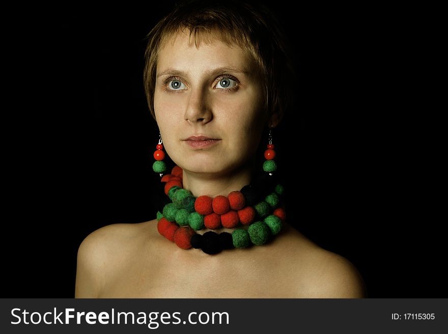 Young woman with bare shoulders in her wearing a necklace and earrings made of wool. Ethnos. Young woman with bare shoulders in her wearing a necklace and earrings made of wool. Ethnos
