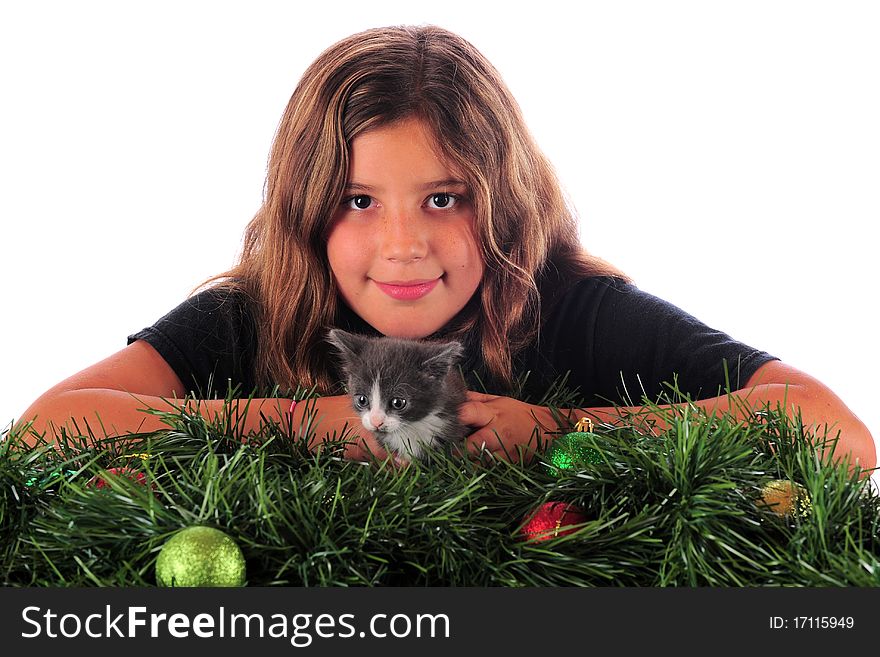 A happy preteen girl posing with her kitten among Christmas greenery. Isolated on white. A happy preteen girl posing with her kitten among Christmas greenery. Isolated on white.