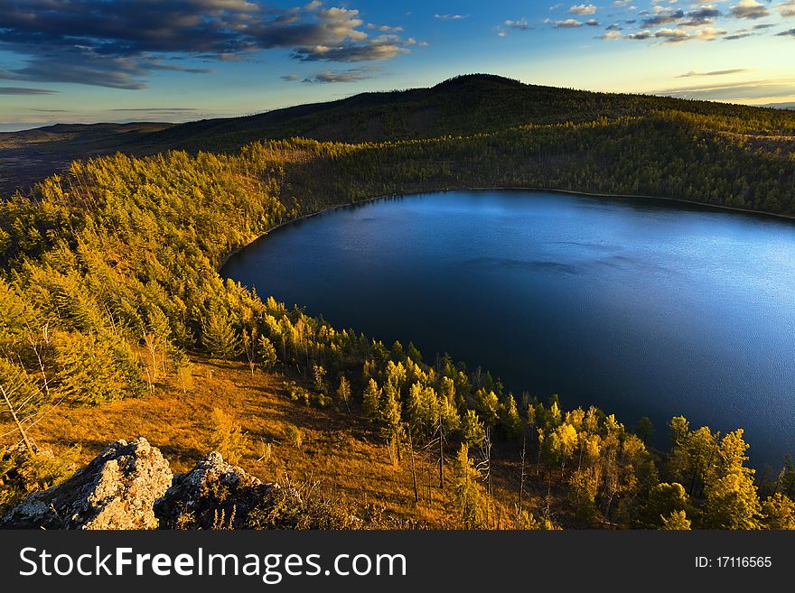 This is a picture of the sunset under the lake and forest.