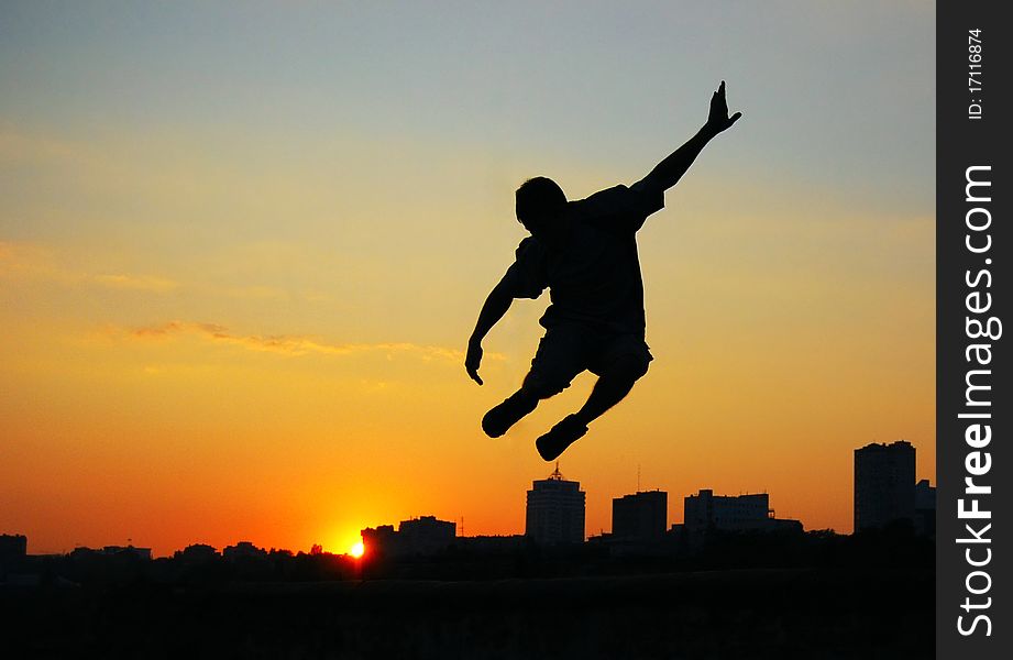A man in a jump over the city at sunset. A man in a jump over the city at sunset