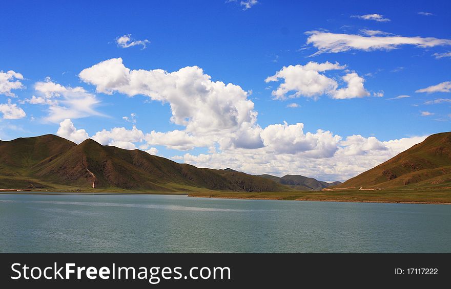 The picture is taken in Tibet. the mountains stand on both sides of the lake. the grass is green and the cloud is white. The picture is taken in Tibet. the mountains stand on both sides of the lake. the grass is green and the cloud is white.