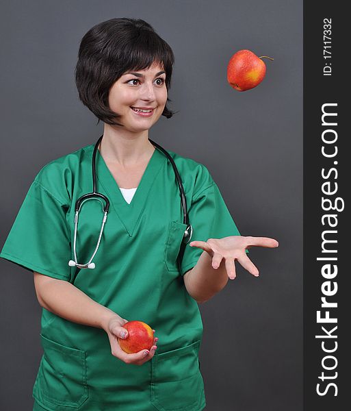 Attractive lady doctor and fresh apples on gray background