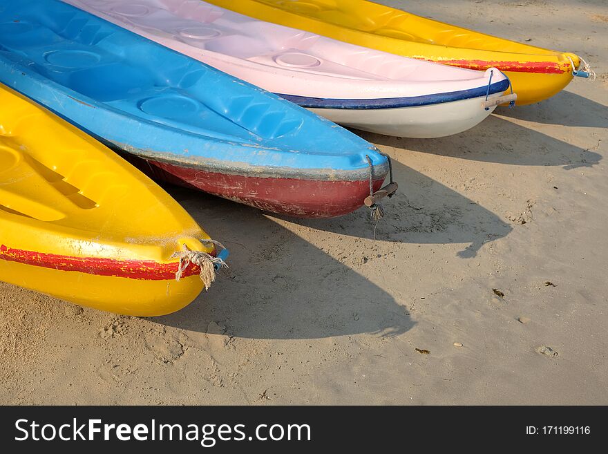 Kayaks stacked on sand beach. Colorful boats in front of sea coast.