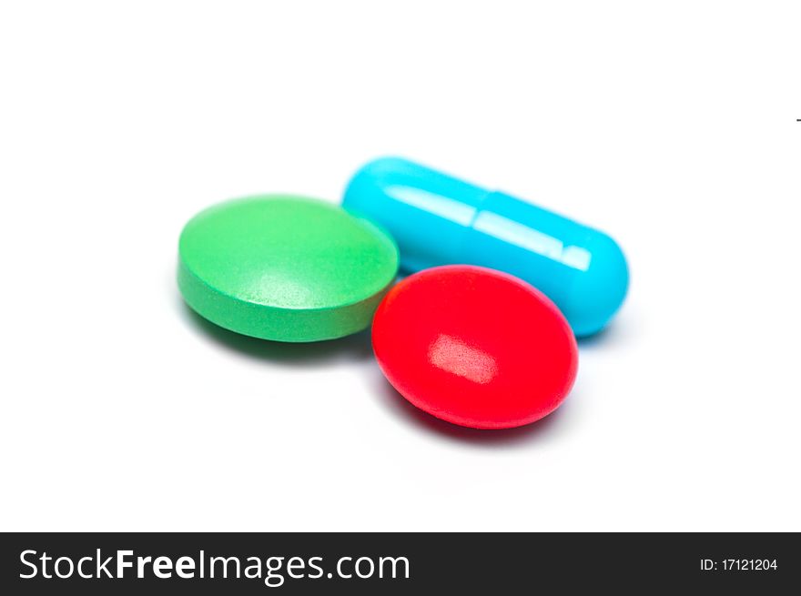 Three multicolored pills on white background