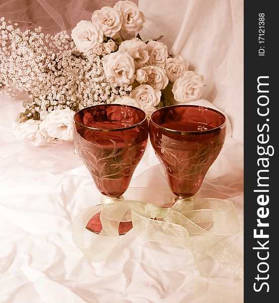 Toned photograph.A bouquet of roses and two glasses. Toned photograph.A bouquet of roses and two glasses