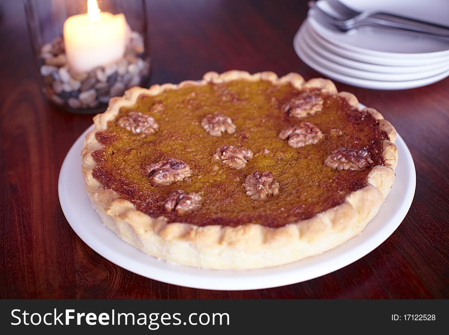 Pumpkin pie with walnuts on a plate with a candle.