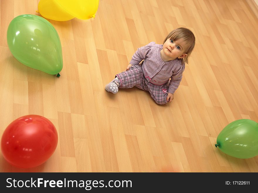 Small child sits in the middle of many colorful balloons, Copy Space