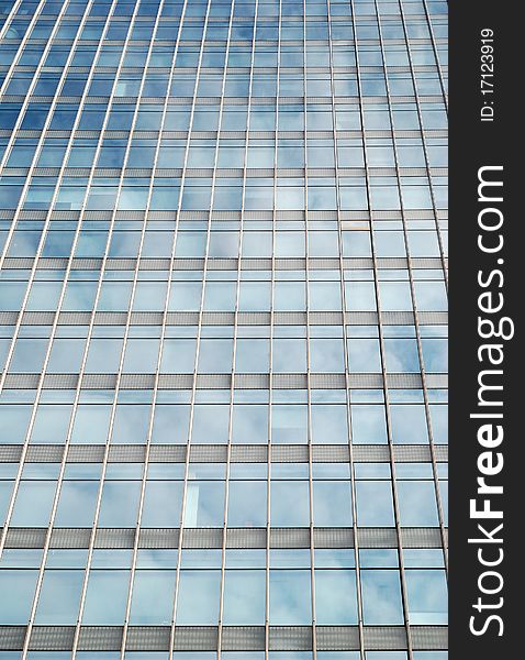 Modern building reflecting blue sky and clouds in the office windows.