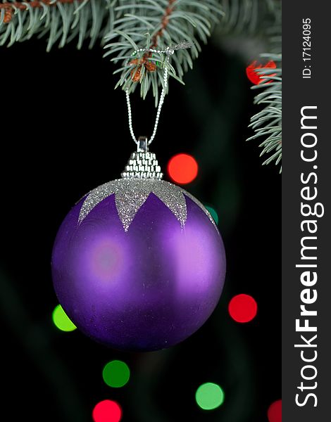 Violet christmas ball with a christmas tree on the black background