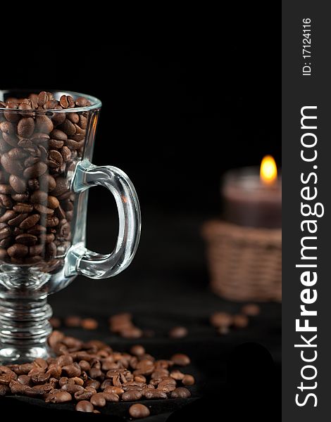 Fragrant fried coffee beans on the glass with burning candle. Fragrant fried coffee beans on the glass with burning candle