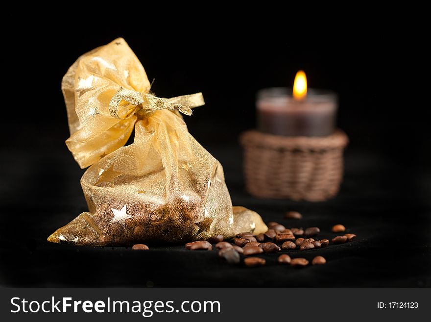Golden christmas sack with the coffee beans and burning candle. Golden christmas sack with the coffee beans and burning candle