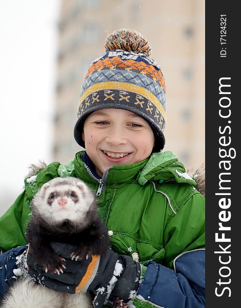 The boy holds a polecat, In the winter in the street