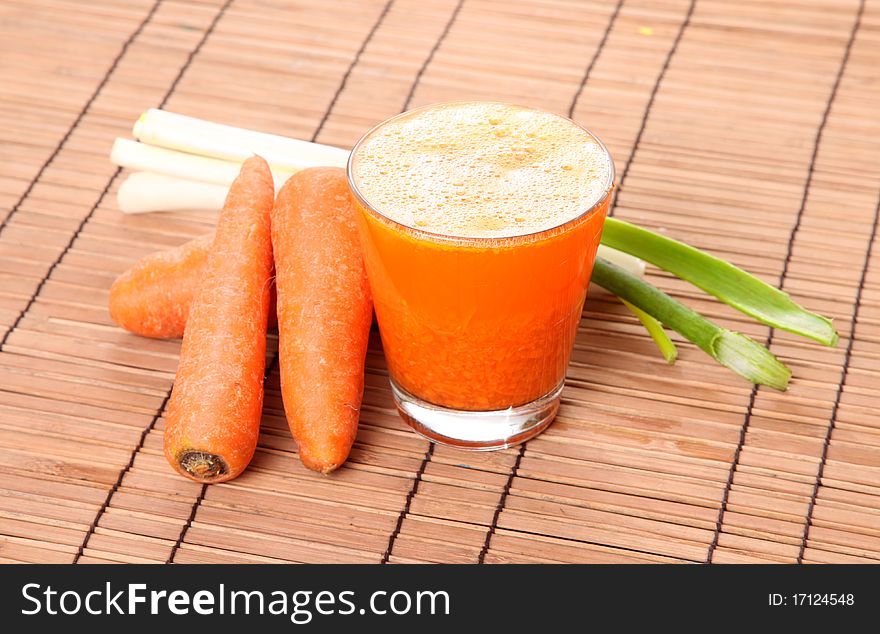 Carrot juice with vegetables over bamboo background